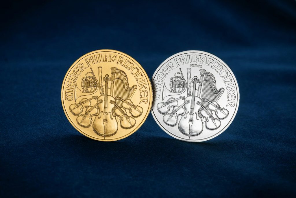 Gold and silver Vienna Philharmonic bullion coins displayed side by side on a dark background, illustrating Silver in an IRA, sd-IRA, silver for IRA, silver in an IRA, and SIlver in IRA as examples of precious metals used in retirement investing.