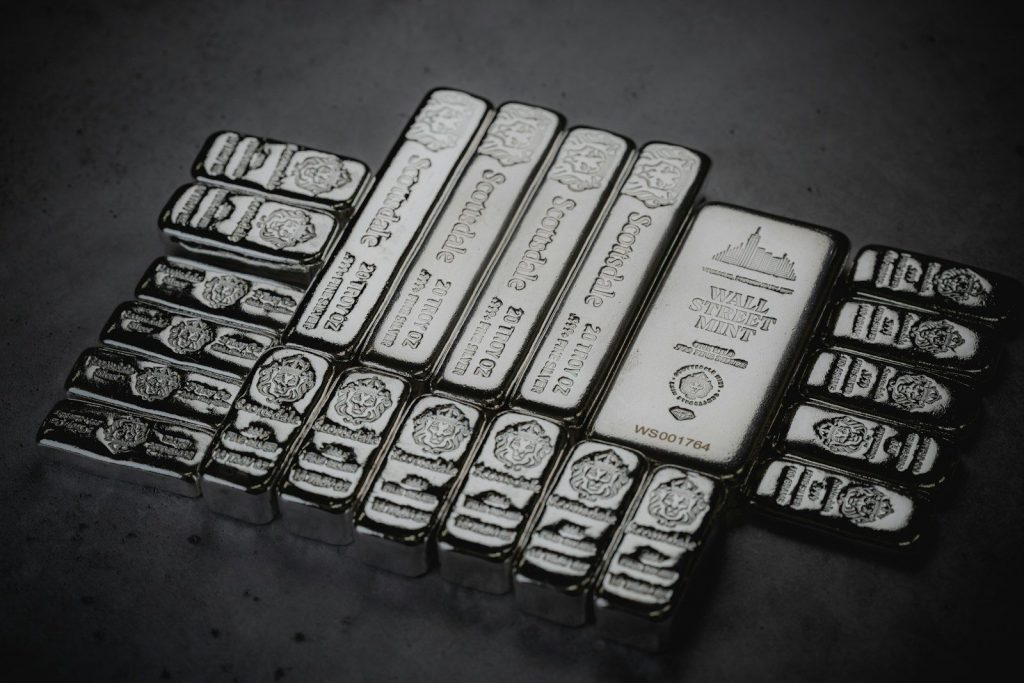 Silver bullion bars arranged on a dark surface, representing Gold and silver investing, explaining what is a gold IRA, exploring Fidelity Gold IRA options, comparing gold IRAs, and answering the question can Roth IRA invest in gold? for retirement diversification.